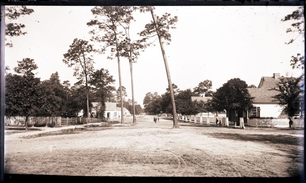 1880 – 1895: A wide sand street with pines down the middle